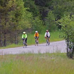 Three bike riders bike along a road in Aspen, Colorado