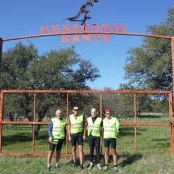 group of 4 people in front of a ranch sign