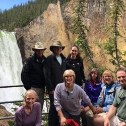 A group poses in front of a waterfall in Yellowstone National Park