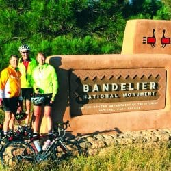 bikers in front of the Bandelier Monument sign