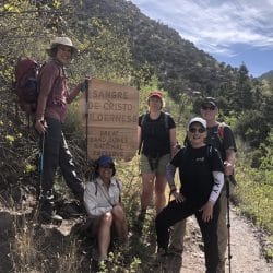 Group of happy hikers next to a trail sign